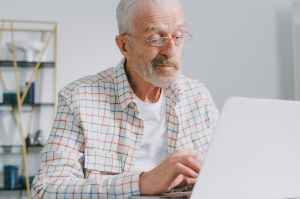 elderly man with eyeglasses working on his laptop
