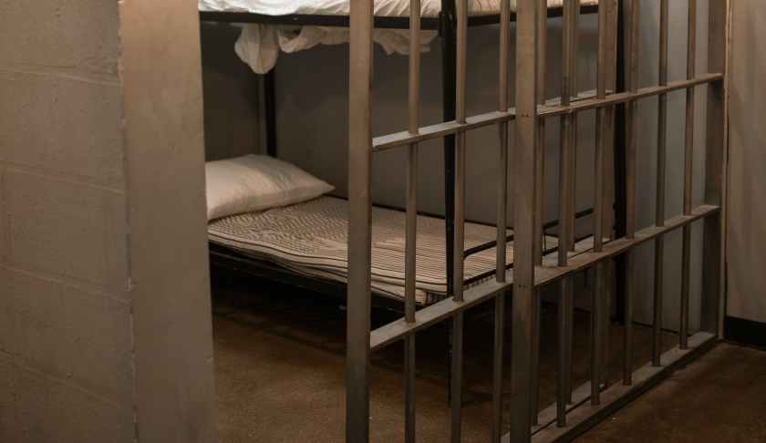 a bunk bed with striped linen behind bars