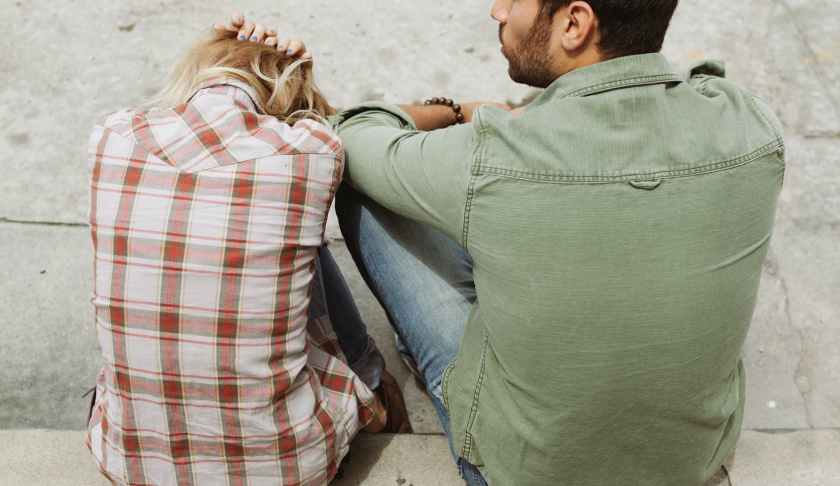 man and woman sitting on sidewalk