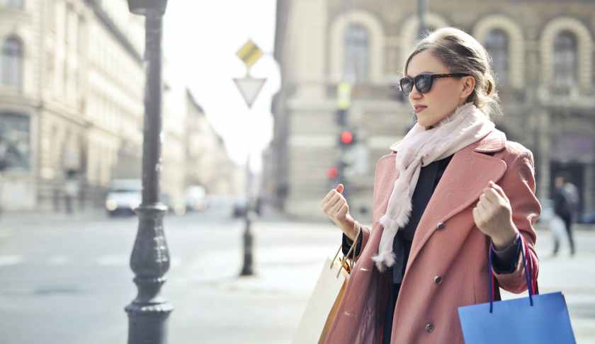 woman in pink coat holding shopping bags