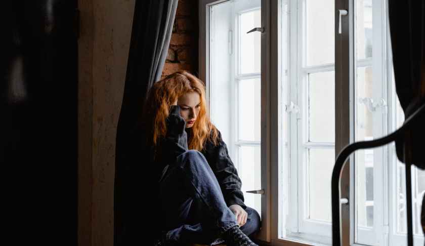 woman in black leather jacket sitting on brown wooden floor