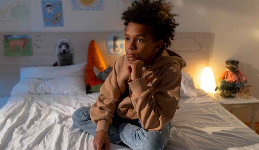 boy sitting on a bed in his room