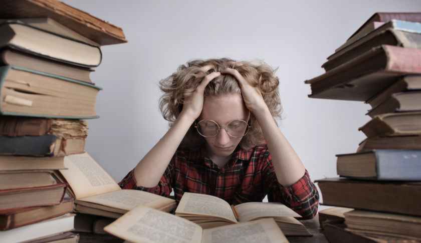 smart teenager reading book at table