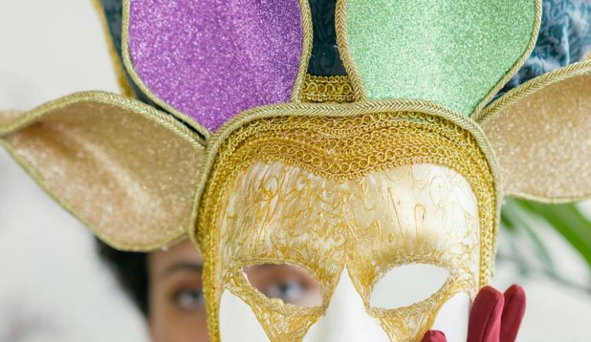 woman holding a mardi gras full face mask