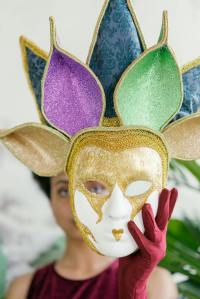 woman holding a mardi gras full face mask