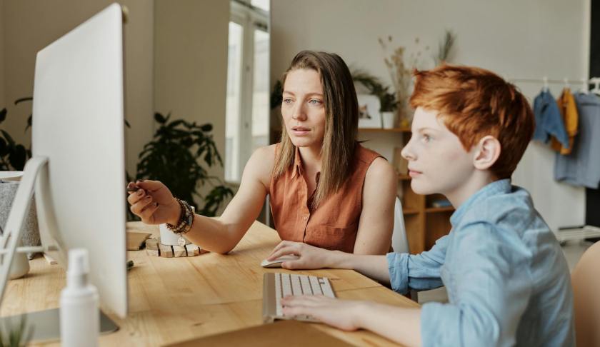 photo of woman tutoring young boy