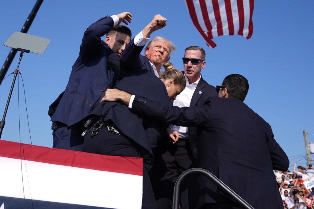 Trump raises fist after being shot at rally. AP Photo by Evan Vucci